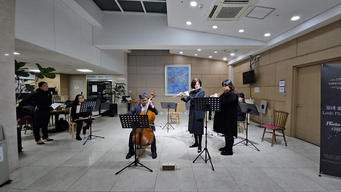 첼로 연주자와 플루트 연주자들이 로비에서 함께 연주하는 모습